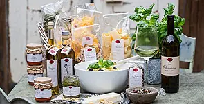 Feinkost: Liköre, Öle, Nudeln und Marmeladen auf einem Holztisch