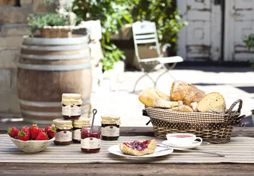 Marmeladen und Kuchen vor einem Weinfass