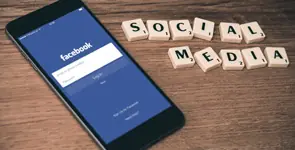 Smartphone mit Facebook neben Buchstaben „Social Media“